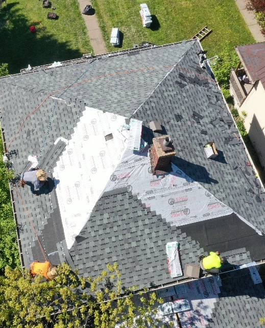 people working on replacing shingles on a roof